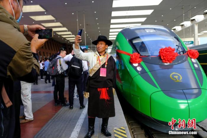 2021年6月25日，川藏铁路拉林段(拉林铁路)正式开通运营，复兴号高原内电双源动车组同步投入运营。拉林铁路全长48公里，设计时速160公里。这是西藏首条电气化铁路，也是复兴号动车组首次开进西藏。图为当日，民众在拉萨火车站复兴号车头前拍照留念。 中新社记者 江飞波 摄